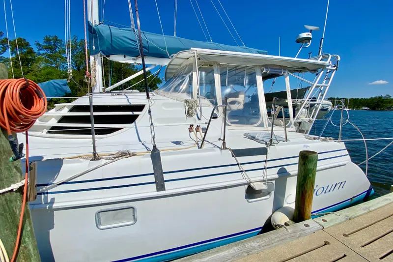 Slide: The Image of 1998 Manta 40 sailboat docked, featuring blue accents and clear canopy under a sunny sky. - 4
