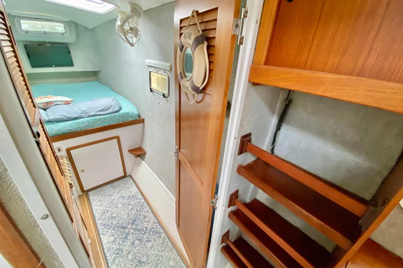 Slide: The Image of Cozy cabin interior of 1998 Manta 40 sailboat with bed and wooden storage shelves. - 47