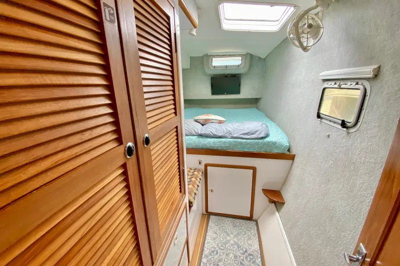 Slide: The Image of Cozy cabin interior of 1998 Manta 40 sailboat with bed, wooden cabinets, and porthole window. - 48