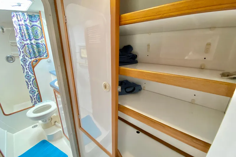 Slide: The Image of 1998 Manta 40 yacht bathroom with storage shelves and colorful shower curtain. - 54