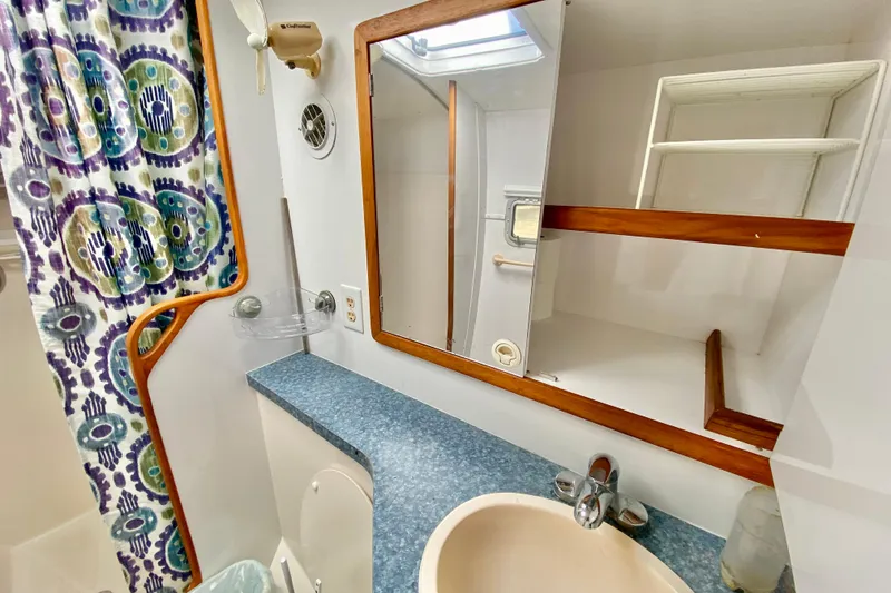 Slide: The Image of 1998 Manta 40 bathroom with patterned curtain, mirror, and blue countertop. - 56