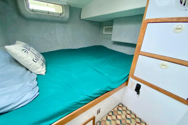 Slide: The Image of Cozy cabin interior of 1998 Manta 40 sailboat with teal bedding and storage. - 60