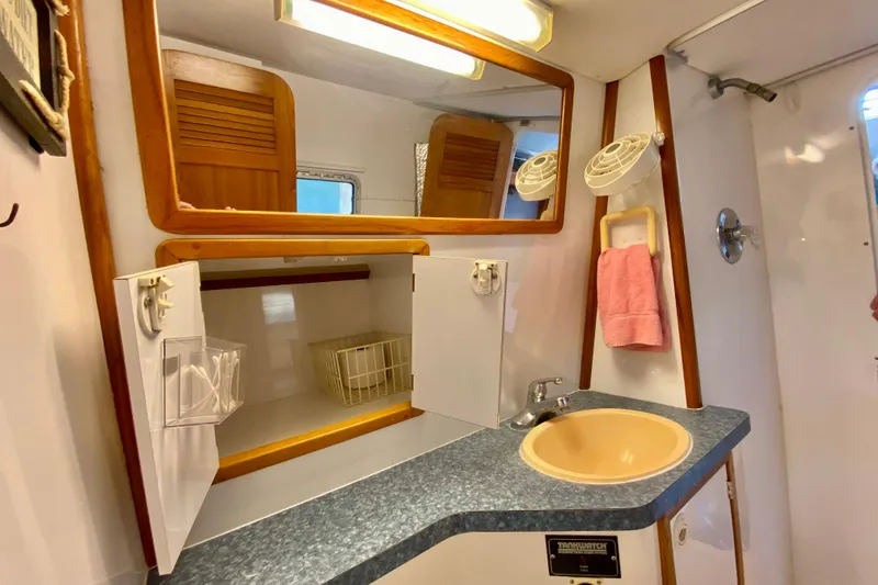 Slide: The Image of Compact bathroom in a 1998 Manta 40 yacht with sink, mirror, and storage cabinets. - 63