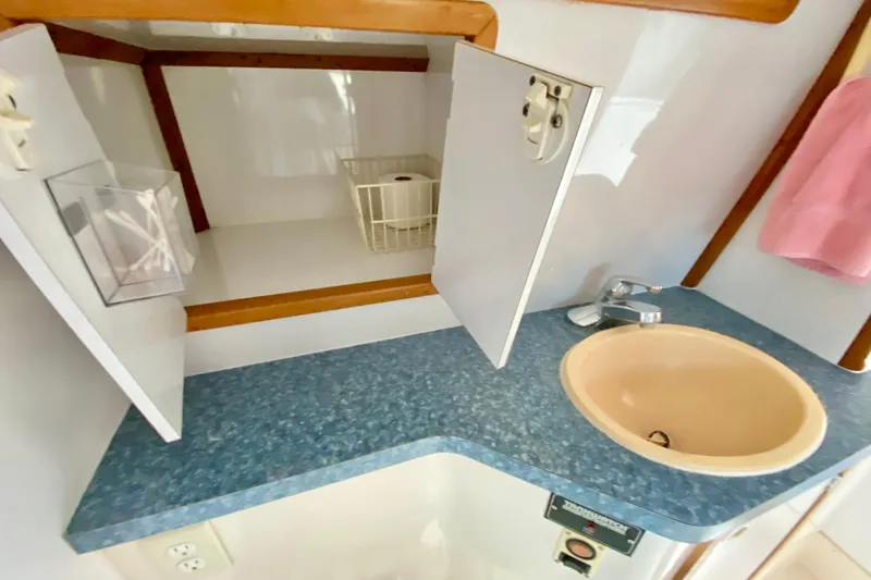 Slide: The Image of 1998 Manta 40 yacht bathroom with blue countertop, sink, and open storage cabinet. - 64