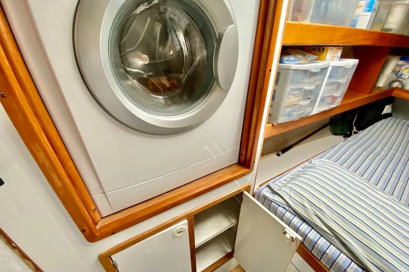 Slide: The Image of Laundry area in a 1998 Manta 40 boat with washer, storage, and striped bedding. - 65