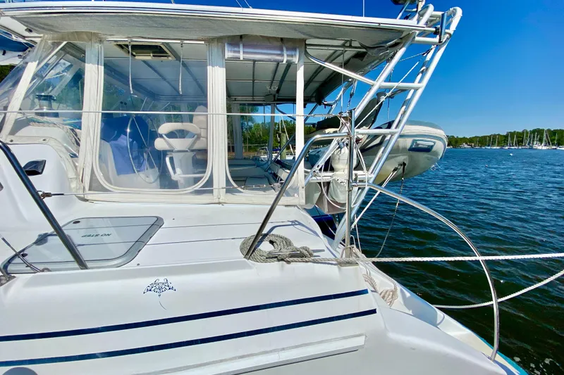 Slide: The Image of 1998 Manta 40 catamaran docked, featuring a spacious cockpit and clear blue waters. - 7