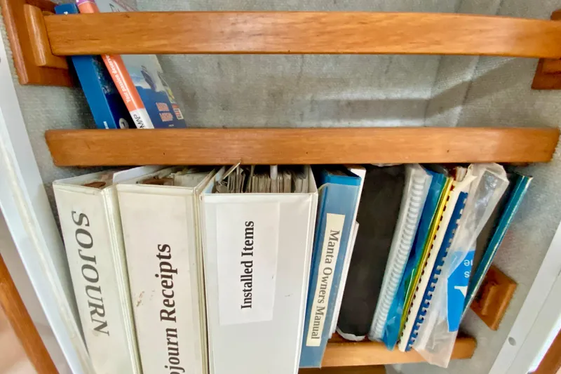 Slide: The Image of Shelf with binders labeled "Sojourn Receipts," "Installed Items," and "Manta Owners Manual," 1998 Manta 40. - 70