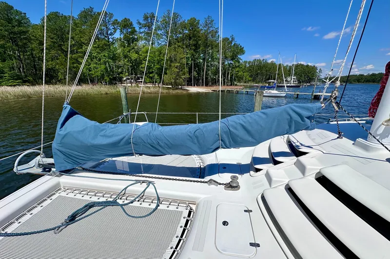 Slide: The Image of Sailboat deck of 1998 Manta 40, docked by a serene lakeside with lush greenery. - 96