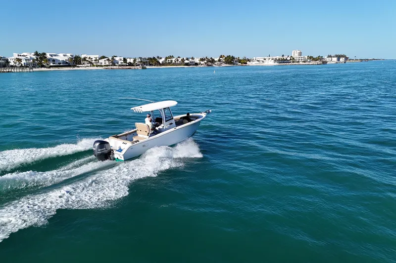 Slide: The Image of 2018 Sea Hunt Ultra 255 SE cruising on clear blue waters near a coastal town. - 5