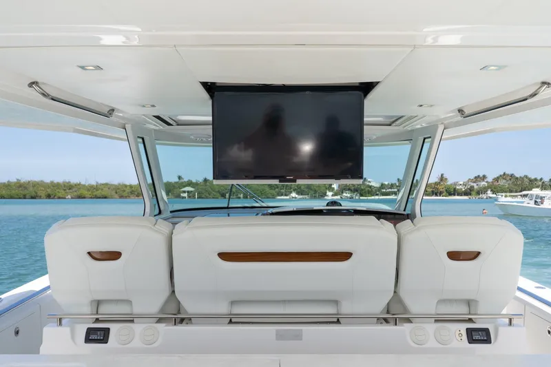 Slide: The Image of 2024 Tiara Yachts 43 LS interior with luxurious seating and a mounted TV, overlooking serene waters. - 23