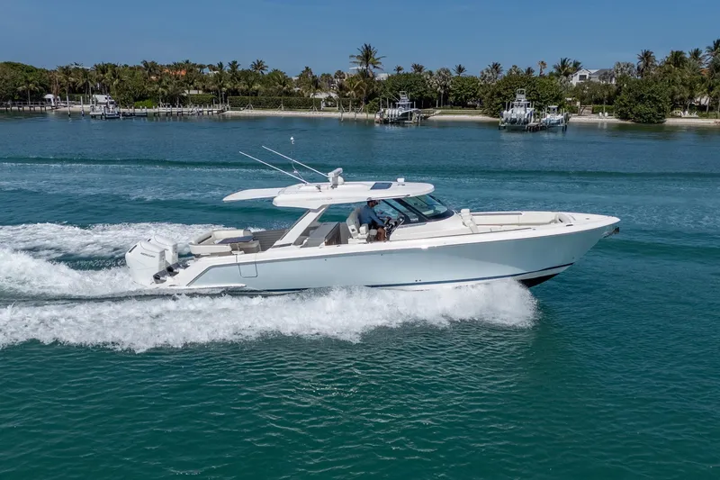 Slide: The Image of 2024 Tiara Yachts 43 LS cruising on clear blue water near a tropical shoreline. - 3