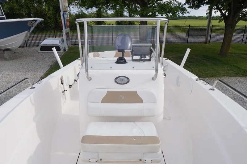 Slide: The Image of 2015 Edgewater 170CC boat interior with console and seating, parked outdoors. - 6
