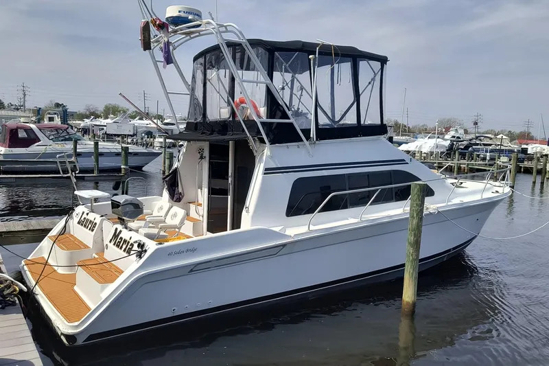 The Image of 1996 Mainship 40 Sedan Bridge yacht docked at marina, featuring spacious deck and flybridge. - 1