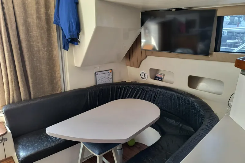 Slide: The Image of Interior of 1996 Mainship 40 Sedan Bridge with dining area and mounted TV. - 10