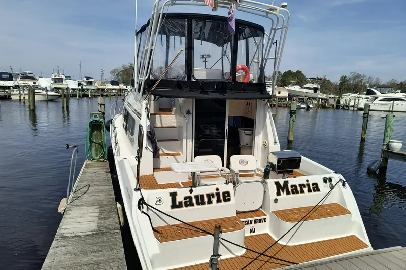 Slide: The Image of 1996 Mainship 40 Sedan Bridge docked at marina, rear view with name "Laurie Maria." - 3