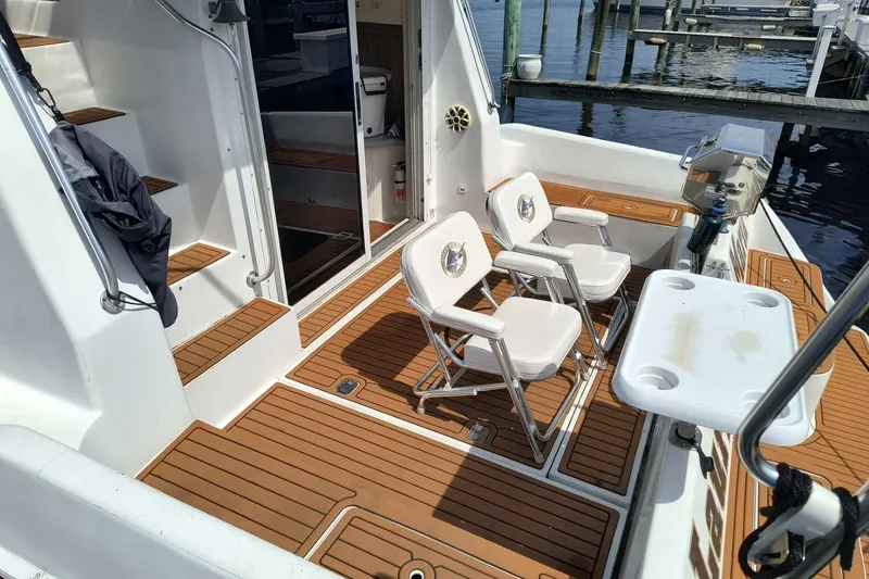 Slide: The Image of 1996 Mainship 40 Sedan Bridge yacht deck with seating and wooden flooring at a marina. - 4