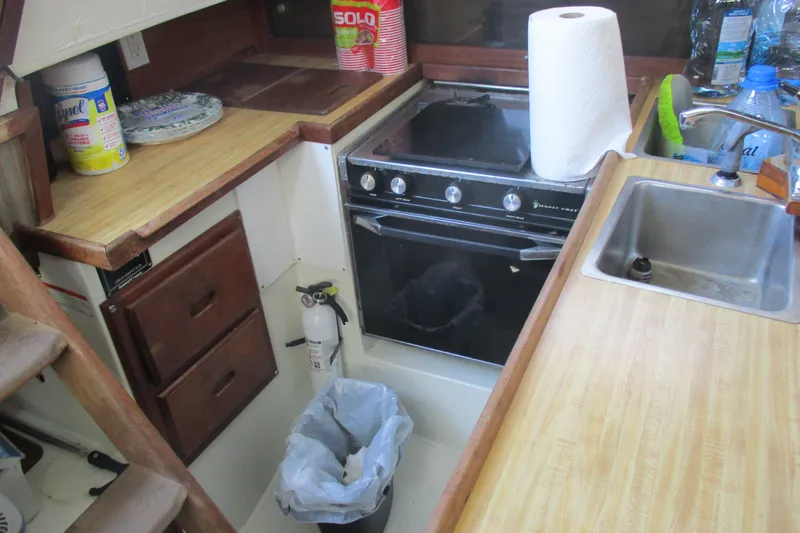 Slide: The Image of 1978 Catalina 30 yacht kitchen with stove, sink, and wooden cabinetry. - 11