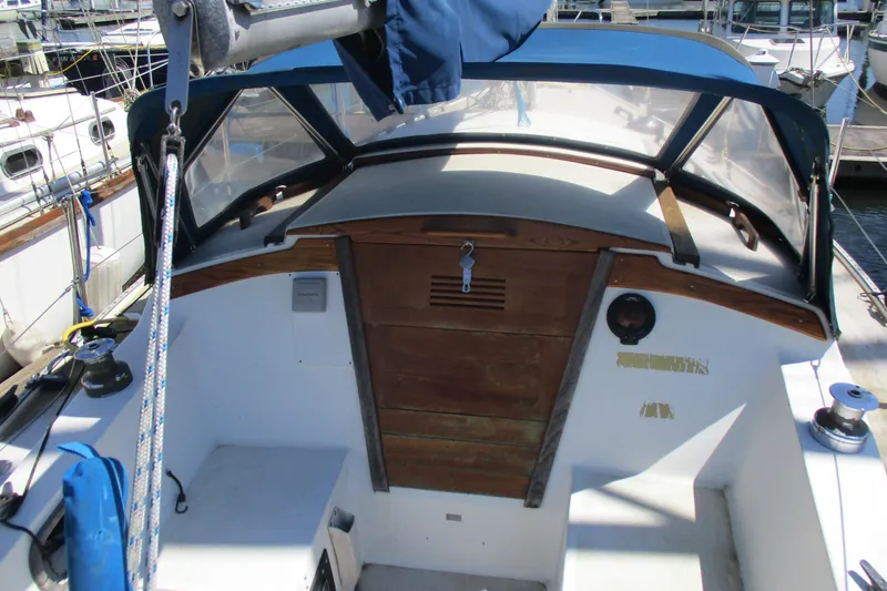 Slide: The Image of 1978 Catalina 30 sailboat cockpit with wooden hatch and blue canopy in marina. - 5