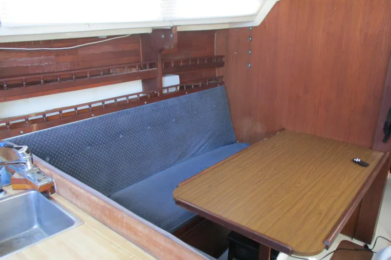 Slide: The Image of Interior of a 1978 Catalina 30 sailboat with a wooden table and blue cushioned seating. - 7