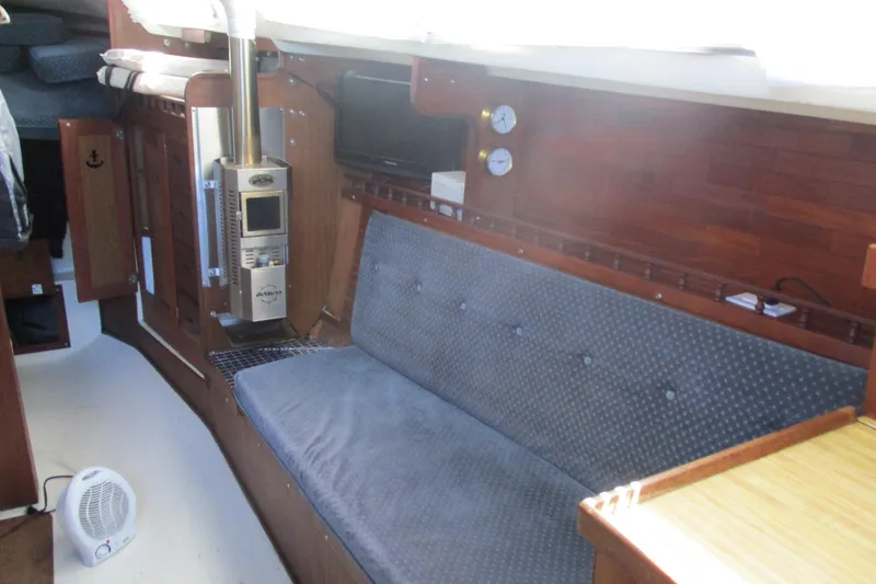Slide: The Image of 1978 Catalina 30 yacht interior with wood paneling, cozy seating, and a compact heater. - 8
