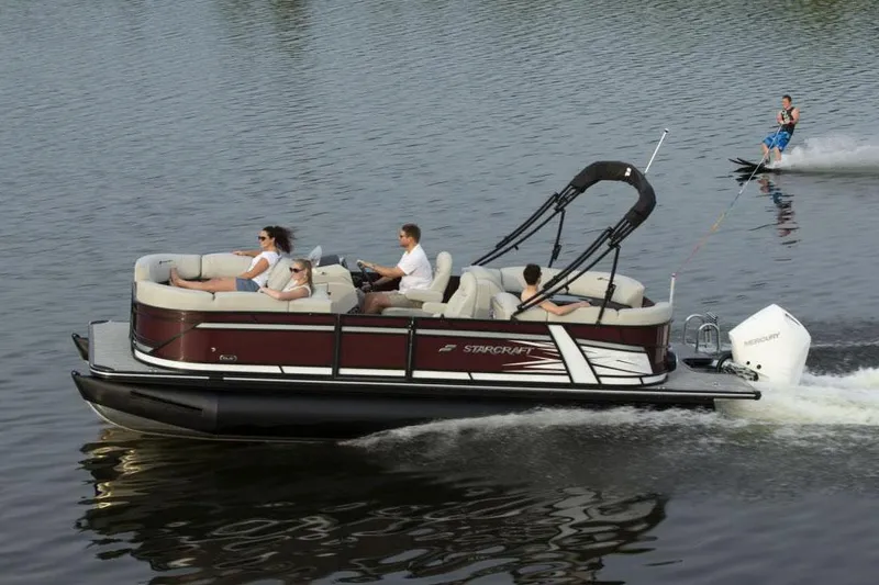 Slide: The Image of Manufacturer Provided Image: 2021 Starcraft SLS 3 pontoon boat towing a water skier on a lake. - 4