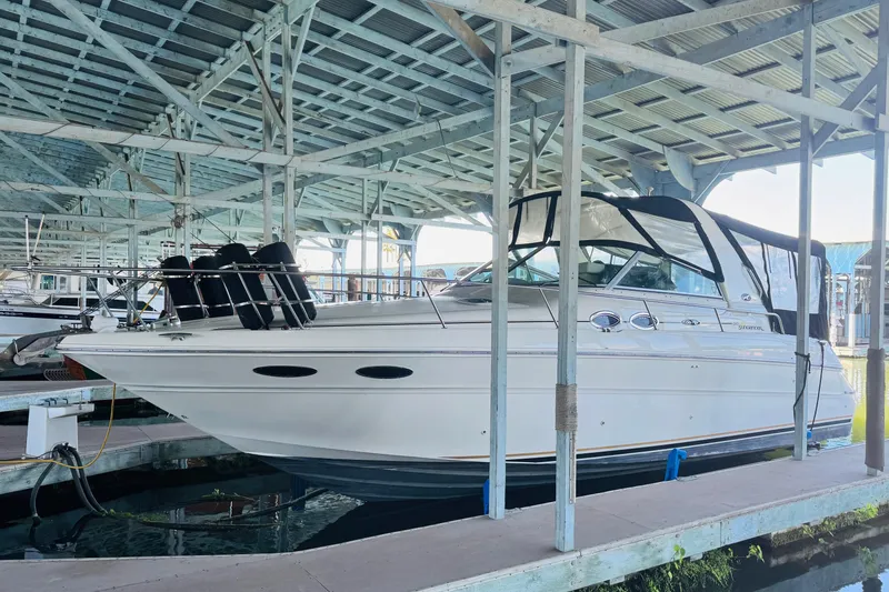 The Image of 2001 Sea Ray Sundancer 310 docked under covered marina, showcasing sleek design and white exterior. - 0