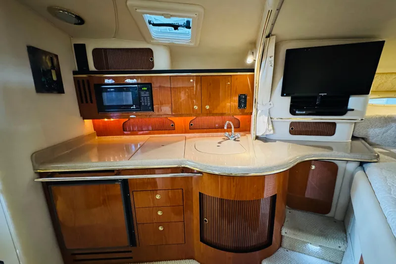Slide: The Image of 2001 Sea Ray Sundancer 310 interior kitchen with wood cabinetry, microwave, and TV. - 37