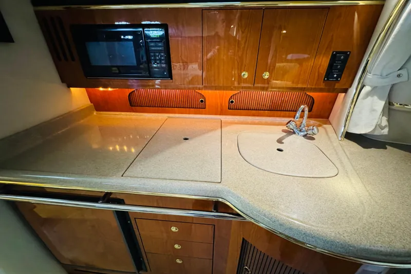 Slide: The Image of 2001 Sea Ray Sundancer 310 galley with microwave, sink, and wooden cabinetry. - 38