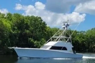 The Image of 1986 Huckins Sport Fisherman boat cruising on a scenic waterway with lush greenery. - 1