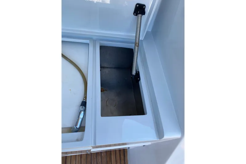 Slide: The Image of 1986 Huckins Sport Fisherman boat compartment with hose and storage area. - 12