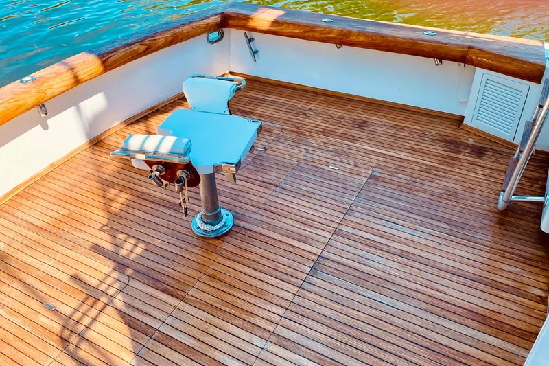 Slide: The Image of 1986 Huckins Sport Fisherman boat deck with wooden flooring and fishing chair. - 14