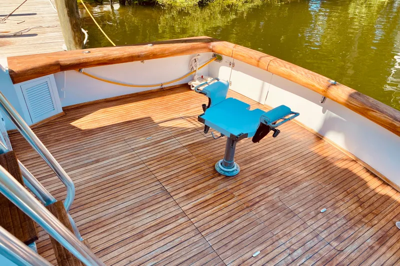 Slide: The Image of 1986 Huckins Sport Fisherman boat deck with wooden flooring and fishing chair. - 15