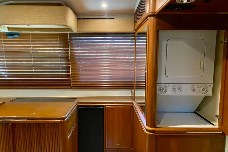 Slide: The Image of 1986 Huckins Sport Fisherman interior with wood cabinetry, blinds, and a stacked washer-dryer unit. - 20