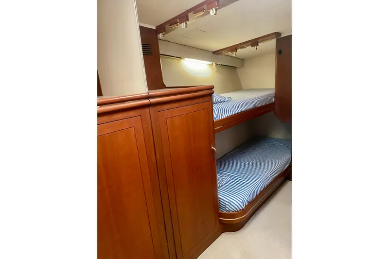 Slide: The Image of 1986 Huckins Sport Fisherman cabin with wooden bunk beds and striped bedding. - 24