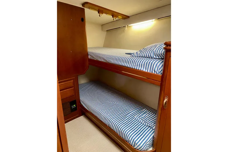 Slide: The Image of 1986 Huckins Sport Fisherman cabin with striped bunk beds and wooden interior. - 25