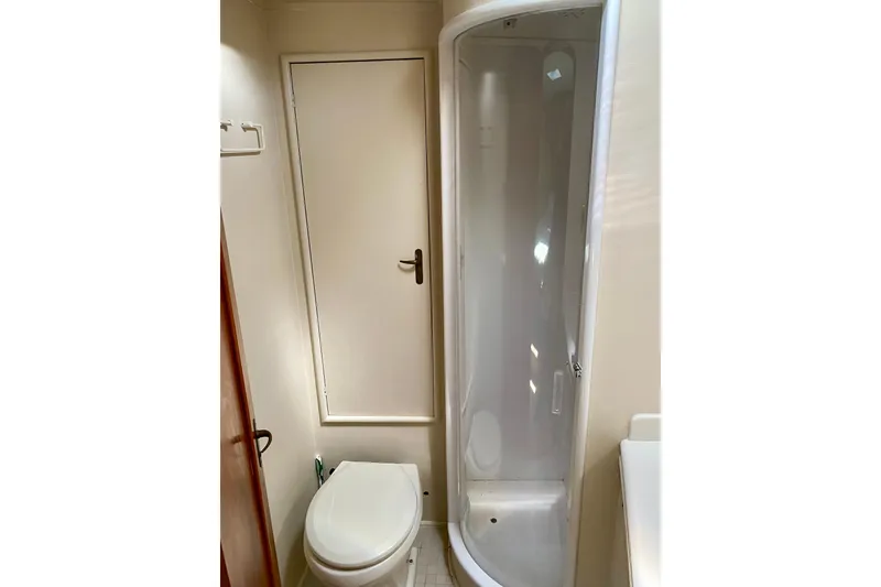 Slide: The Image of Compact bathroom in a 1986 Huckins Sport Fisherman yacht, featuring a shower and toilet. - 28