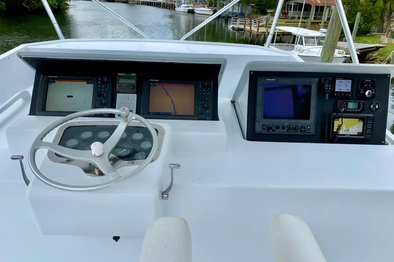 Slide: The Image of 1986 Huckins Sport Fisherman helm with navigation equipment and steering wheel on a calm waterway. - 3