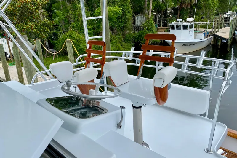 Slide: The Image of 1986 Huckins Sport Fisherman boat with white seating and wooden accents at a dock. - 8