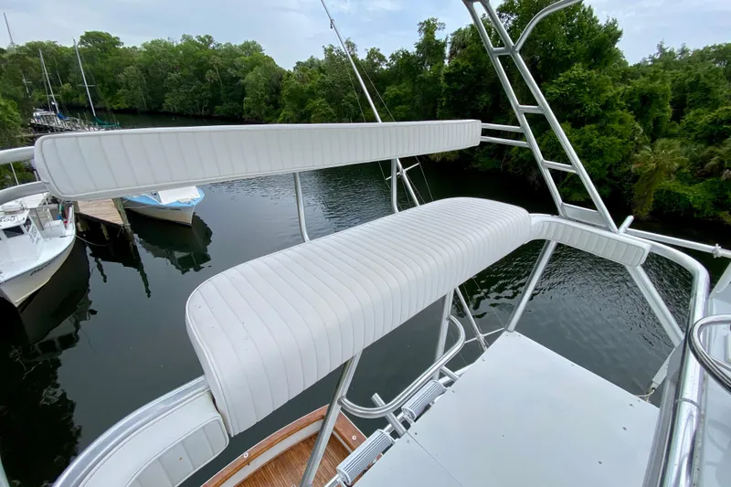Slide: The Image of 1986 Huckins Sport Fisherman boat with white seating, overlooking a serene river and lush greenery. - 9