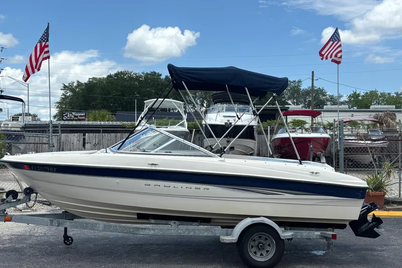 The Image of 2003 Bayliner 185 Capri boat on trailer with American flags in background. - 1
