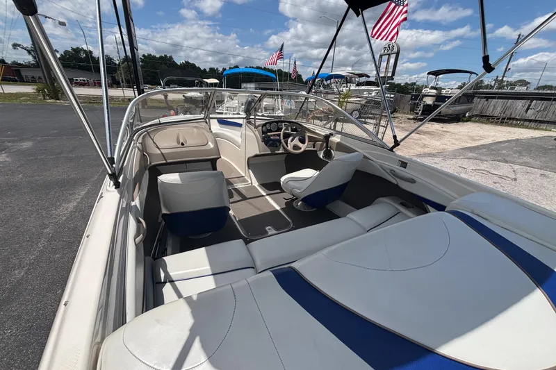 Slide: The Image of 2003 Bayliner 185 Capri boat interior with seating, steering wheel, and canopy under a blue sky. - 13