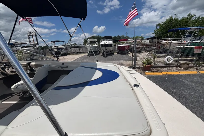 Slide: The Image of 2003 Bayliner 185 Capri boat with canopy, parked in a marina under a blue sky. - 14