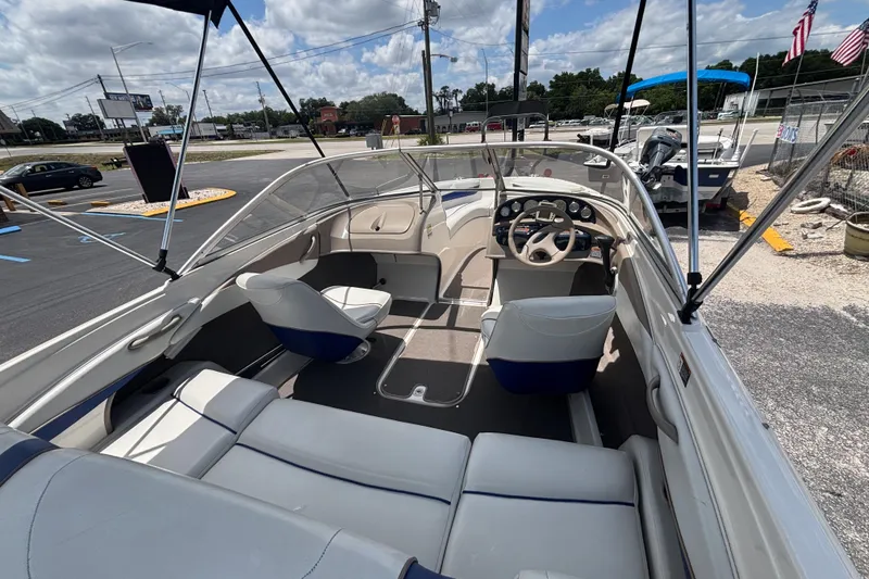 Slide: The Image of 2003 Bayliner 185 Capri boat interior with seating and steering wheel, parked outdoors. - 17