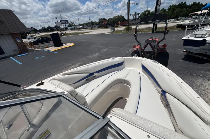 Slide: The Image of 2003 Bayliner 185 Capri boat interior with white seating, parked outdoors under cloudy sky. - 21