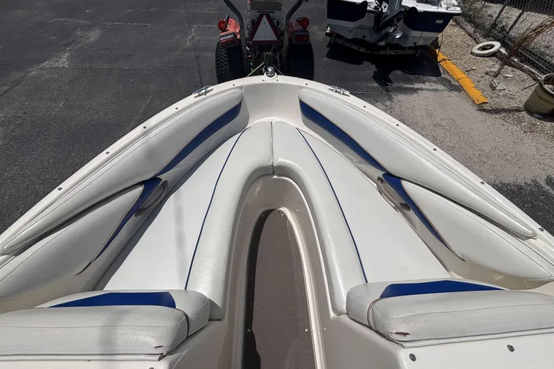 Slide: The Image of 2003 Bayliner 185 Capri boat interior with white and blue seating, parked on pavement. - 26
