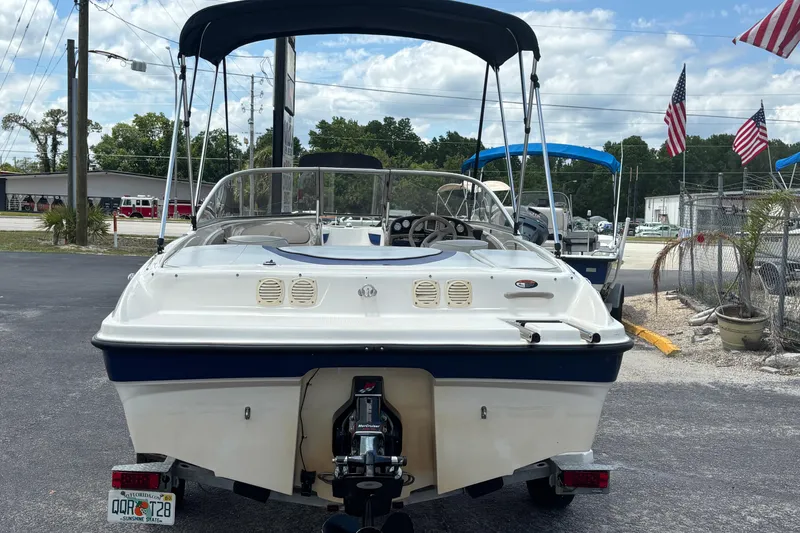 Slide: The Image of 2003 Bayliner 185 Capri boat with canopy, parked outdoors, American flags in background. - 4