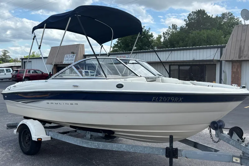 Slide: The Image of 2003 Bayliner 185 Capri boat on trailer with blue canopy, parked outside dealership. - 7
