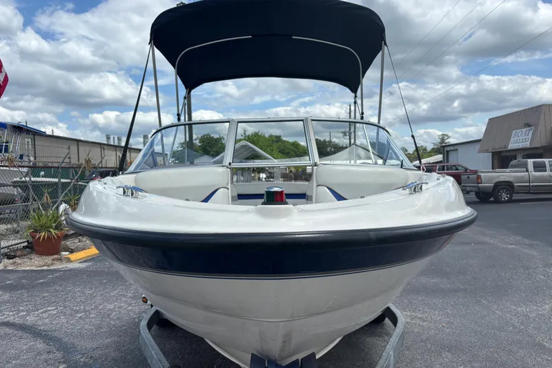 Slide: The Image of 2003 Bayliner 185 Capri boat with canopy, parked outdoors under a cloudy sky. - 8