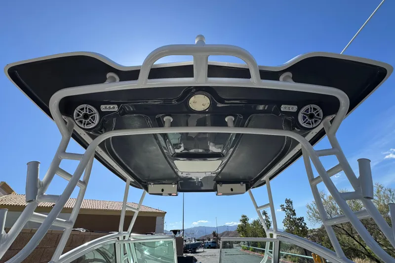 Slide: The Image of 2022 Robalo R247 Dual Console boat with T-top and speakers under clear blue sky. - 18