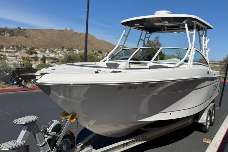 Slide: The Image of 2022 Robalo R247 Dual Console boat on trailer, parked outdoors with scenic background. - 3